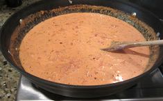 a pan filled with food sitting on top of a stove next to a wooden spoon