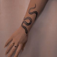 a woman's hand with a snake tattoo on her left arm and the wrist