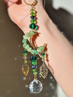 a woman's hand holding onto a bracelet with charms and leaves on it,