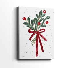 a white canvas with a red ribbon and holly berry decoration on the front, hanging on a wall