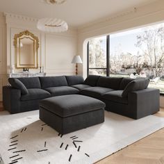 a living room with a large sectional couch and ottoman in front of a big window