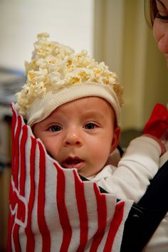 a baby in a red and white striped bib with popcorn on it's head