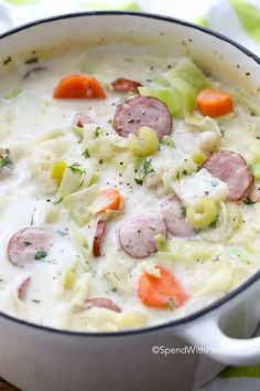 a pot full of soup with carrots, broccoli and meat in it