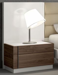 a nightstand with a lamp on it next to a bed