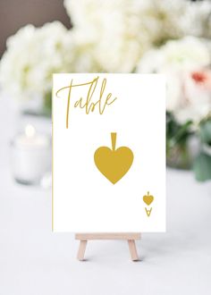 a card with a heart on it sitting on top of a table next to flowers