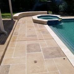 an outdoor swimming pool and patio area with stone pavers, tile flooring and steps leading up to it