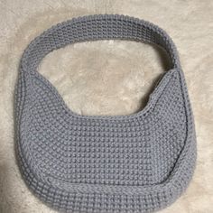 a gray crocheted purse sitting on top of a white rug