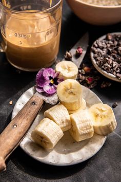 sliced bananas on a plate next to a bowl of granola and a glass of coffee