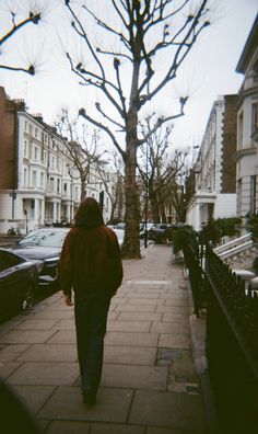 a person walking down a sidewalk next to parked cars