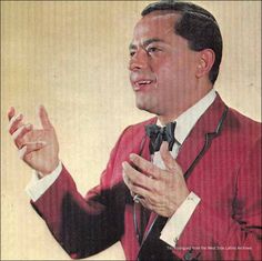 a man in a red suit and bow tie holding his hands out to the side