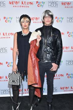 two people standing next to each other in front of a white wall with the words hello kitty written on it