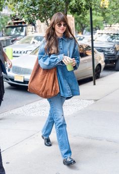 a woman walking down the street with a cup in her hand