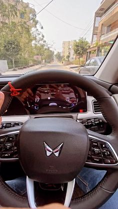 a person is holding the steering wheel in their car, while they are working on an electronic device