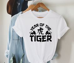 2022 Year Of The Tiger Shirts, Happy Chinese New Year 2022, China Shirt gift, Chinese Tiger, Animal Lover Shirt, Wild Animal Shirt Ideas GUIDANCE *All our simple color t-shirts are 100% Cotton. *All our Heather Color t-shirts are 90% cotton 10% polyester blend and they are extremely snug. Our design are made very professionally with the right equipment *Soft and High-Quality Fabric *Taped shoulder-to-shoulder *Tear away label *Retail fit *Pre-shrunk * Side Seamed *Design size and placement is ap Casual Graphic Print Tops For New Year, New Year White Short Sleeve Tops, White Short Sleeve Top For New Year, Casual Short Sleeve Tops For New Year, Tiger Shirts, Chinese New Year 2022, Chinese Tiger, 2022 Year, Tiger Shirt