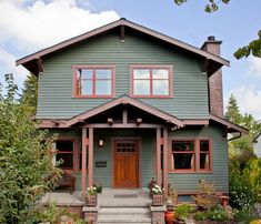 a green house with red trim on the front door and steps leading up to it