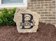 a rock with the letter b on it in front of a house