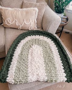 a crocheted afghan sitting on top of a couch next to a pillow and chair