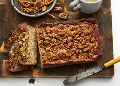 a loaf of bread sitting on top of a cutting board next to a bowl of pecans