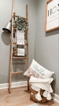 a ladder leaning up against the wall next to a basket filled with pillows and blankets