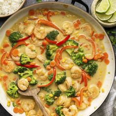 a skillet filled with shrimp, broccoli and carrots