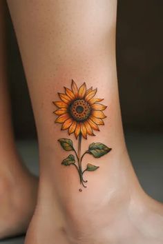 a sunflower tattoo on the ankle is shown in this image, it has green leaves