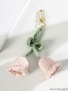 two crocheted bells attached to a keychain on a white surface with a metal hook