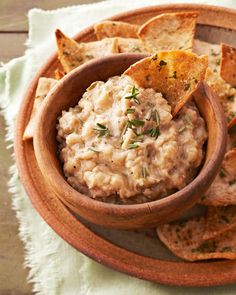 a wooden bowl filled with dip surrounded by tortilla chips