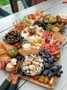 an assortment of cheeses, crackers, nuts and fruit on a platter