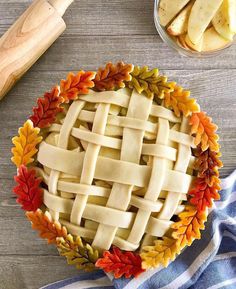 an apple pie on a wooden table with autumn leaves