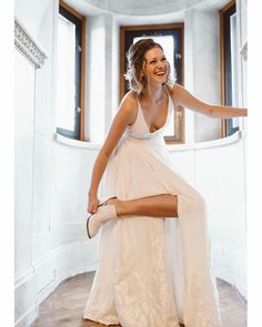 a woman in a white dress sitting on the floor with her legs spread out and smiling