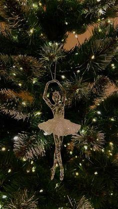 a ballerina ornament hanging from the top of a christmas tree with lights