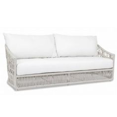 a white wicker couch with two pillows on the back and one pillow in front