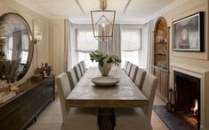 a dining room table with chairs and a vase on it in front of a fire place