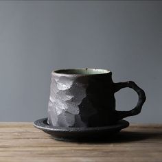 a black cup sitting on top of a wooden table