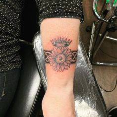 a woman's foot with a crown and flower tattoo on her left calf sleeve