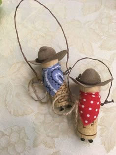 two wine corks with hats and clothes on them sitting on a white tablecloth