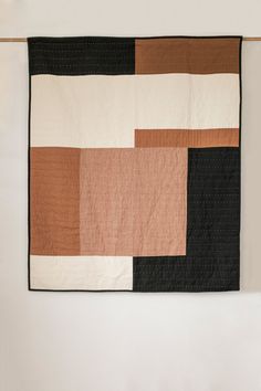 a black, brown and white quilt hanging on a wall