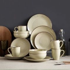 a table topped with white dishes and cups