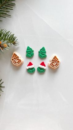 four christmas cookies sitting on top of a white surface next to a pine tree branch