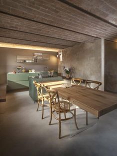 a table and chairs in a room next to a wall with exposed brick ceilinging