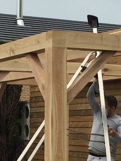 two men are working on the roof of a house that is being built with wood