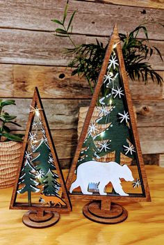 two wooden christmas trees decorated with white snowflakes and a polar bear cutout