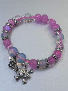 This stunning Opalite bracelet features a vibrant mix of pink beads, complemented by a unique charmed skull for a touch of edgy elegance. Opalite, known for its serene and calming energy, enhances personal power and emotional balance. It is believed to improve communication, clear mental blockages, and help with transitions, making it a perfect companion for navigating life's changes. The soft, iridescent glow of Opalite symbolizes purity and spiritual growth, while the pink beads add a gentle, Trendy Pink Beaded Charm Bracelet, Adjustable Pink Charm Bracelet With 8mm Beads, Trendy Pink Beaded Bracelets With Charms, Bohemian Pink Beaded Charm Bracelet, Casual Pink Beaded Charm Bracelet, Pink Charm Bracelet With Round Beads For Friendship, Pink Round Beads Charm Bracelet For Friendship, Pink Spiritual Charm Bracelet For Friendship, Pink Bohemian Charm Bracelet With Round Beads