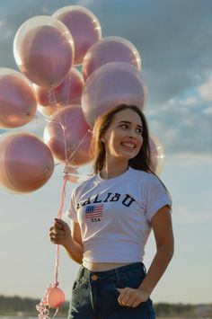 a young woman is holding many balloons in her hands