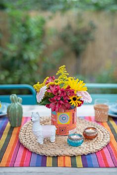 a colorful table setting with flowers in a vase and other items on the placemat