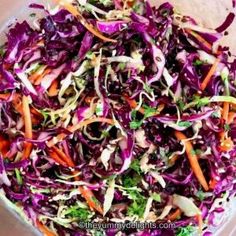 a salad with carrots, cabbage and lettuce in a glass bowl on a table