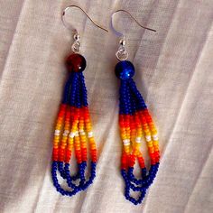 two pairs of beaded earrings on top of a white cloth covered table with fabric