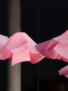 pink paper birds are flying in the air with their wings spread out and they appear to be folded