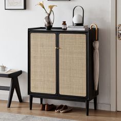 a black cabinet with two doors and some pictures on the wall next to it in a room