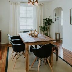 a dining room table with black chairs and a potted plant on the far side